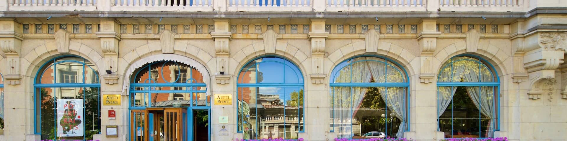 A historic building with ornate balconies, large arched windows, and flower boxes.
