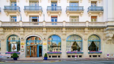 Un edificio histórico con balcones ornamentales, amplias ventanas de arco y jardineras con flores.