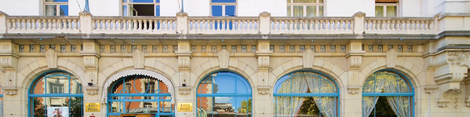 Un edificio histórico con balcones ornamentales, amplias ventanas de arco y jardineras con flores.
