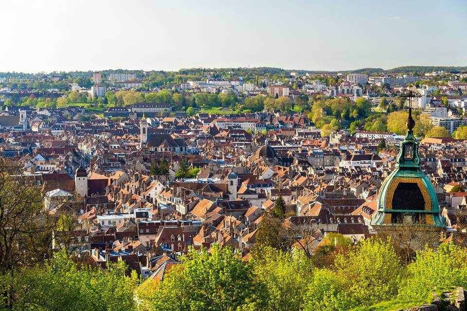 Un paysage urbain dense, caractérisé par des bâtiments historiques et une structure remarquable surmontée d’un dôme vert.