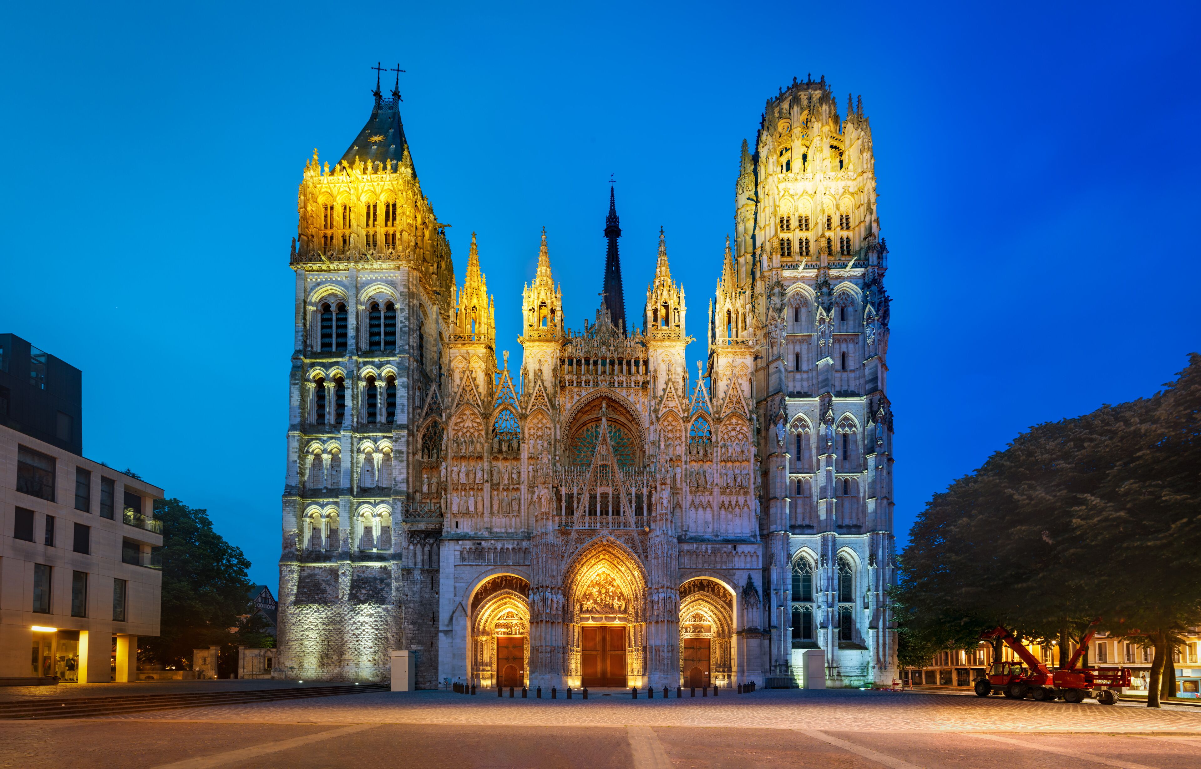 A Gothic cathedral with two towers, illuminated at dusk.