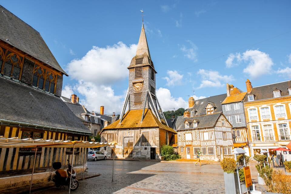 A historic town square with a church tower, cobblestone streets, and traditional half-timbered houses.