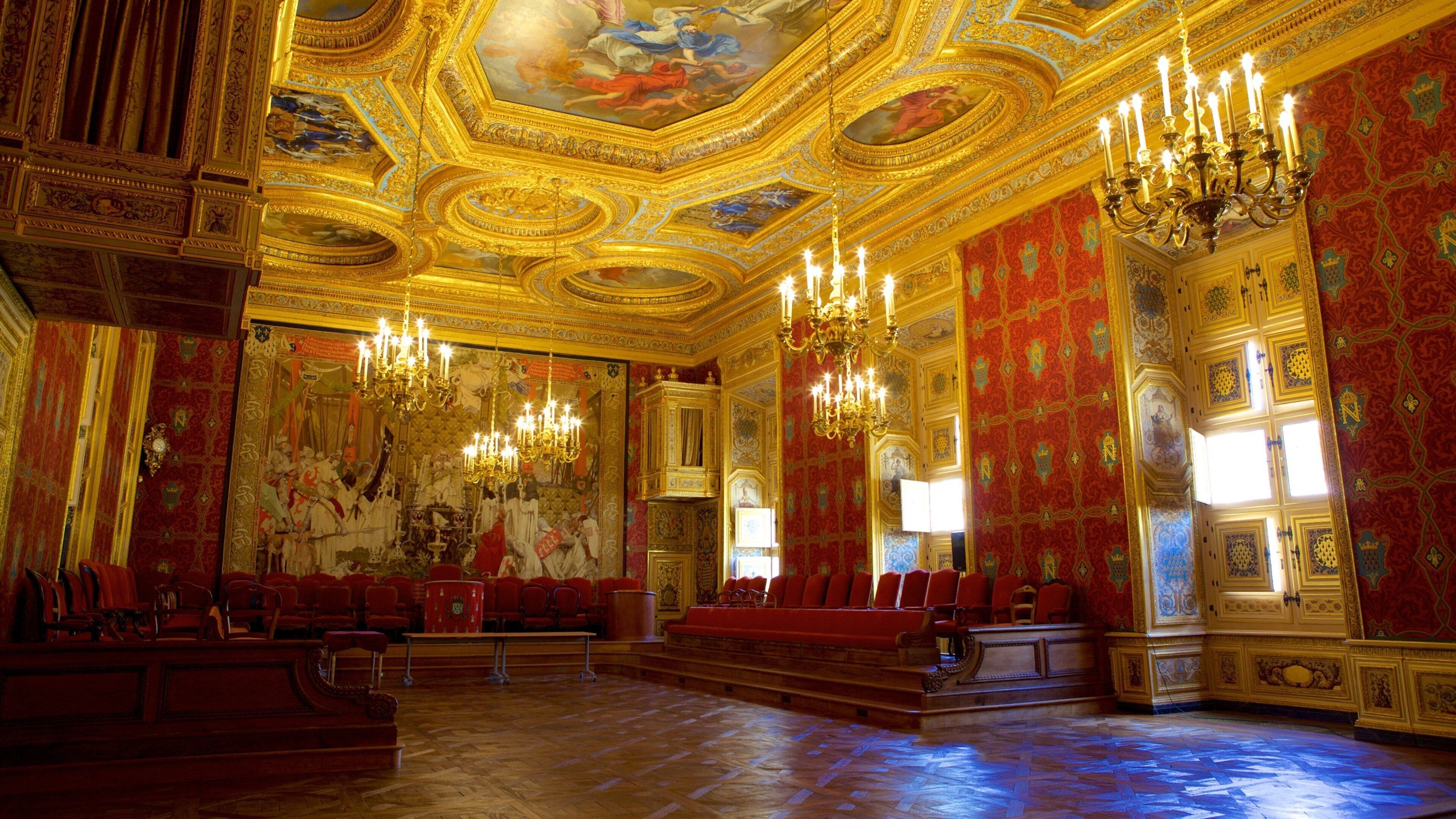 Un hall somptueux, avec des sièges rouges, des lustres dorés et des fresques murales richement décorées.