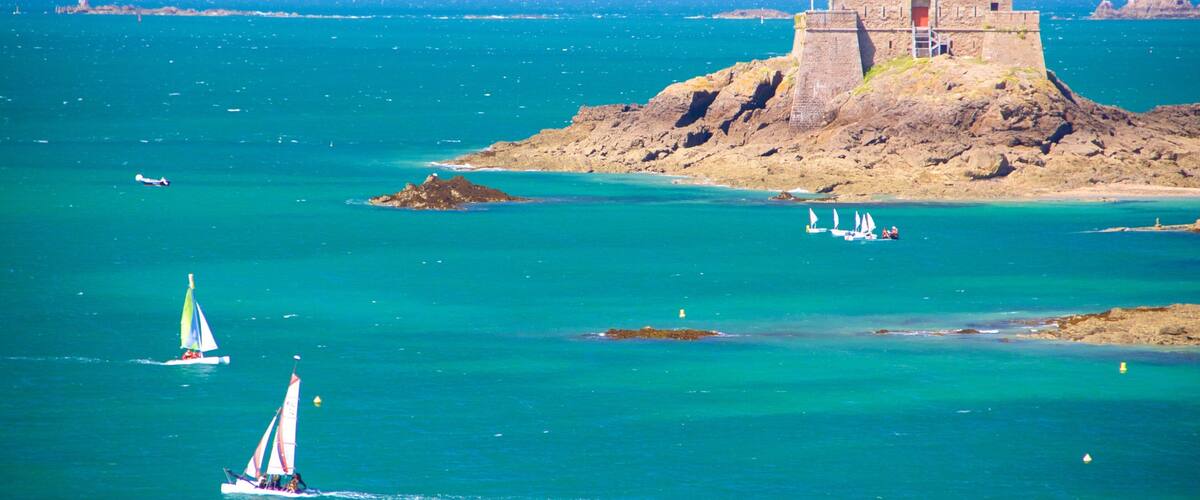 A coastal scene with a lighthouse, a small island with a building, and sailboats on the water.