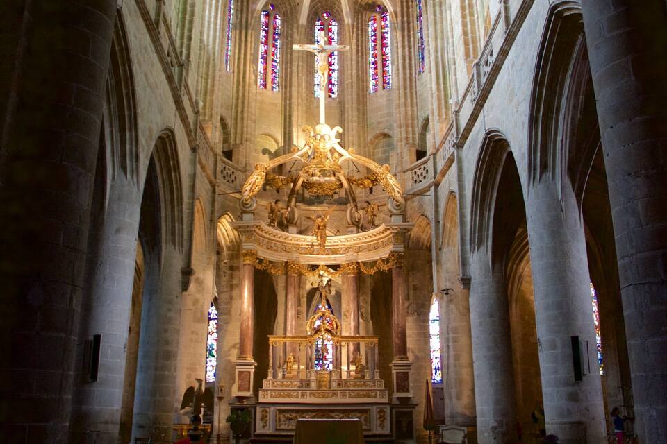 A cathedral interior with a large crucifix, stained glass windows, and ornate altar.