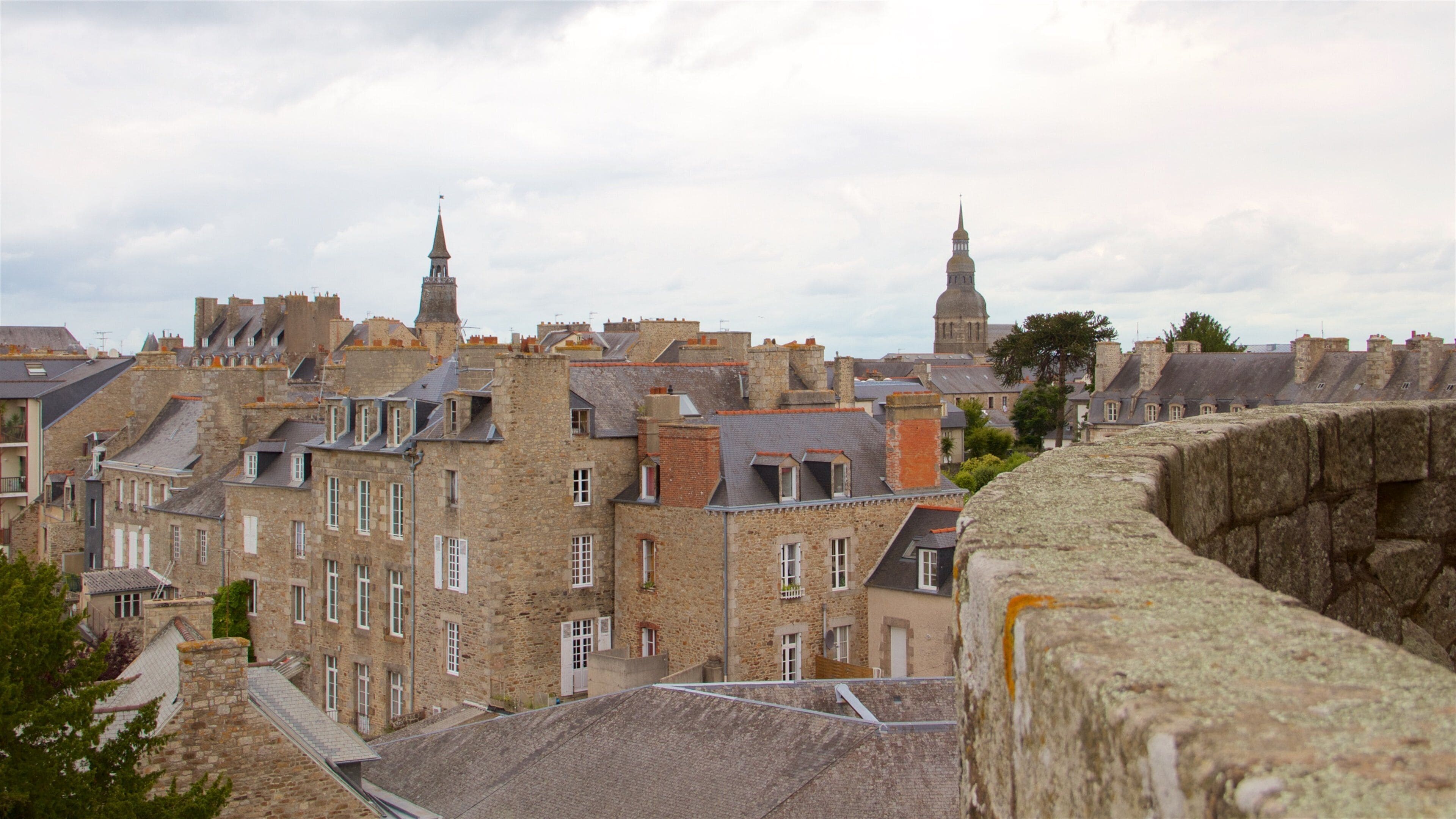 Une ville historique, avec ses bâtiments en pierre, son imposant clocher et ses remparts défensifs.