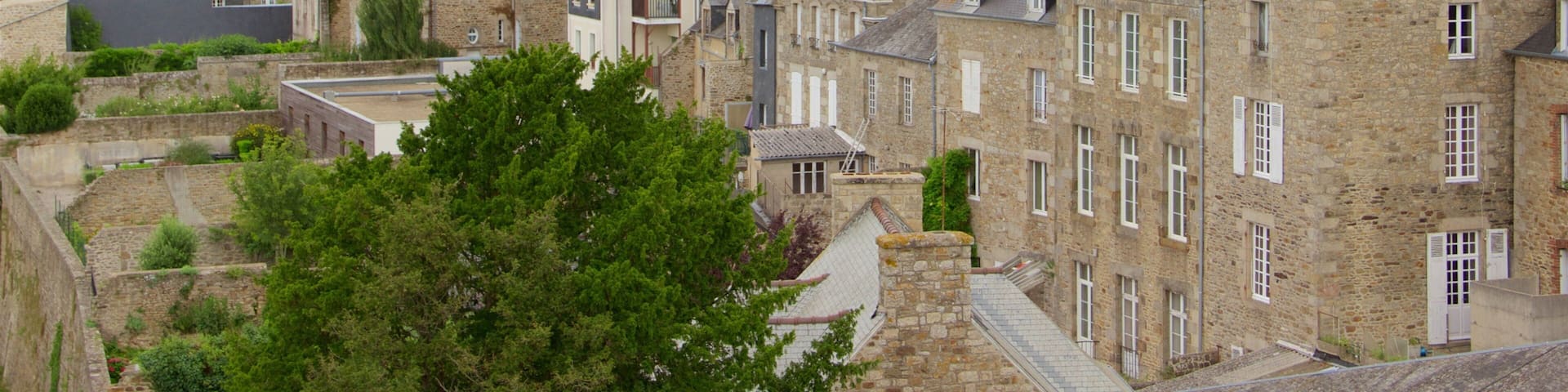 A historic town with stone buildings, a prominent church tower, and lush greenery.