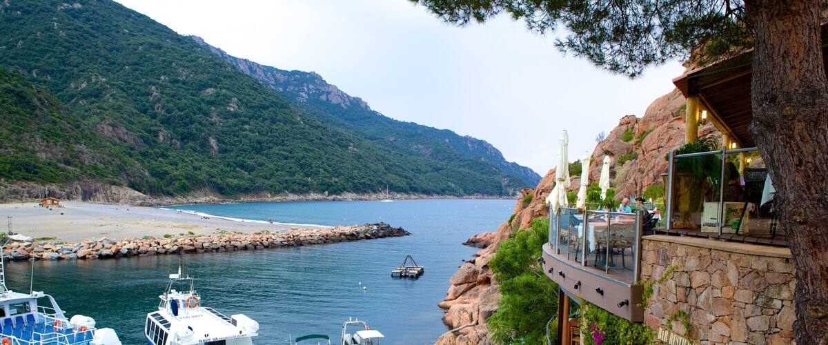A coastal area with boats docked, a rocky shoreline, and a restaurant overlooking the sea.