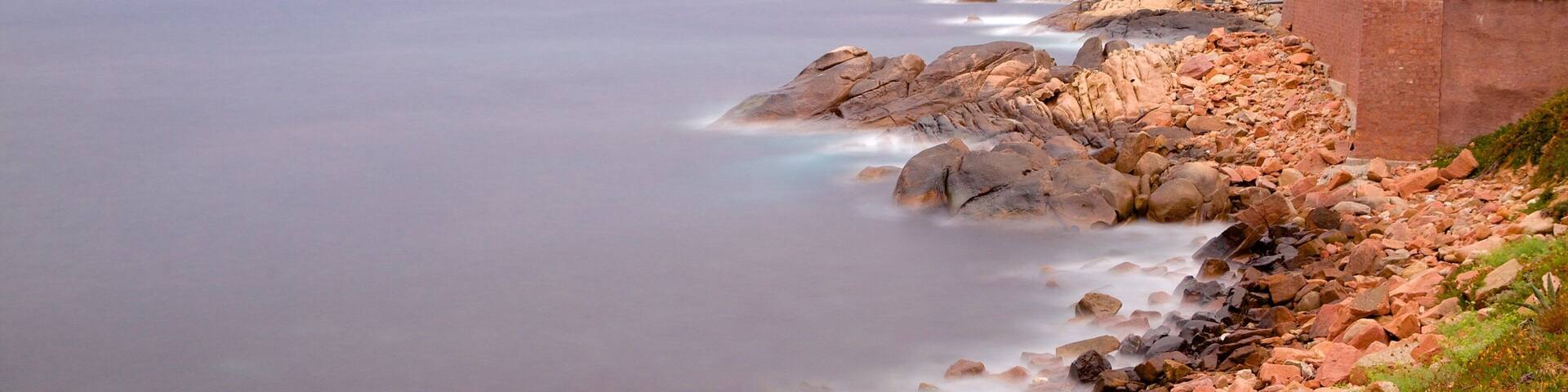 Genuesiska tornet presenterar en solnedgÄng och klippig kustlinje