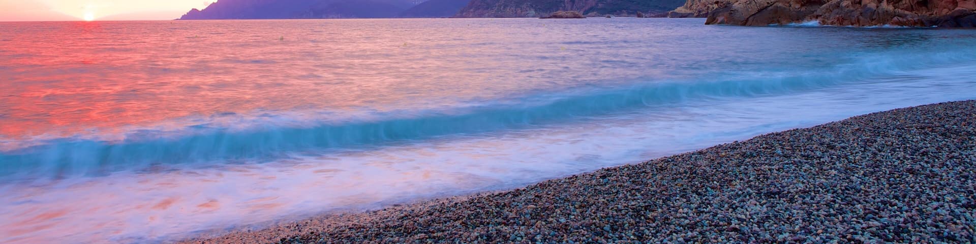 Genoese Tower which includes a sunset and a pebble beach