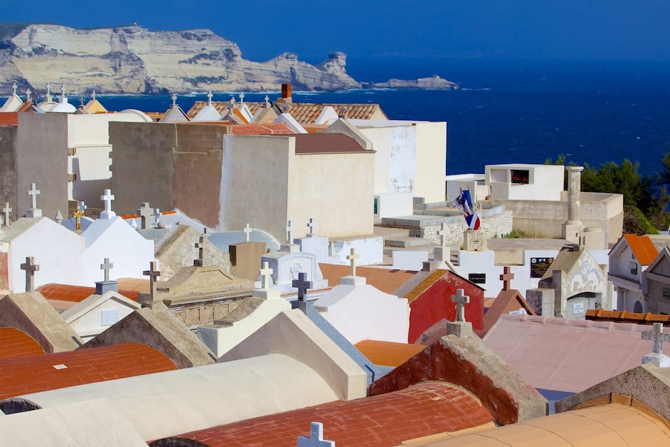 A coastal town with numerous tombs and crosses, a lighthouse, and a cliff in the background.