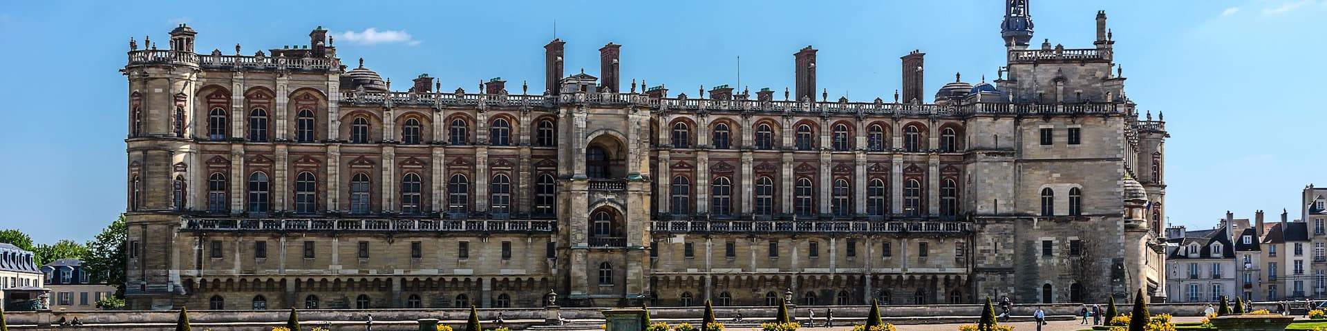 A large historic building with a symmetrical facade, a central courtyard, and a prominent tower.