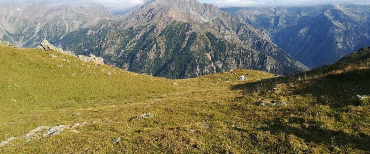 A mountain landscape with grassy slopes and rocky peaks.