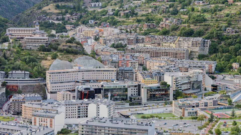 A cityscape with a mix of modern and traditional architecture, surrounded by lush green hills.