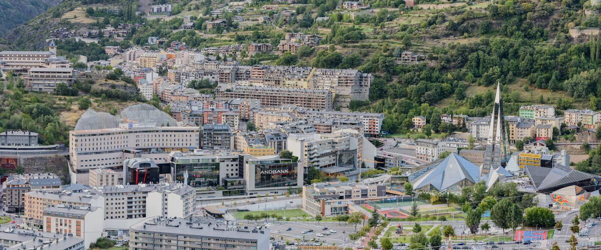A cityscape with a mix of modern and traditional architecture, surrounded by lush green hills.