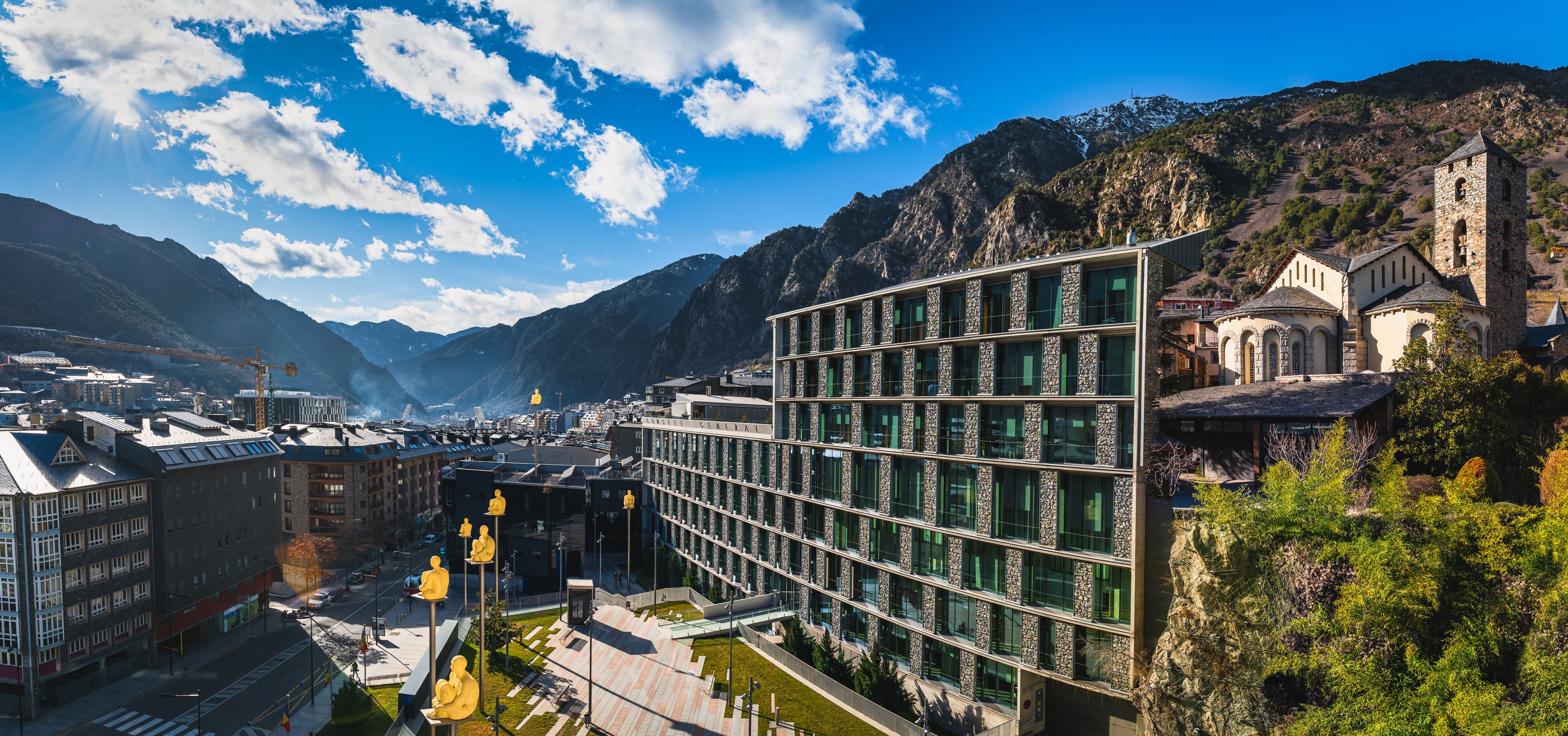 Cityscape of Andorra la Vella capita city of Andorra wit men sitting on poles, at the foothill of Pyrenees Mountain range. St. Esteve church