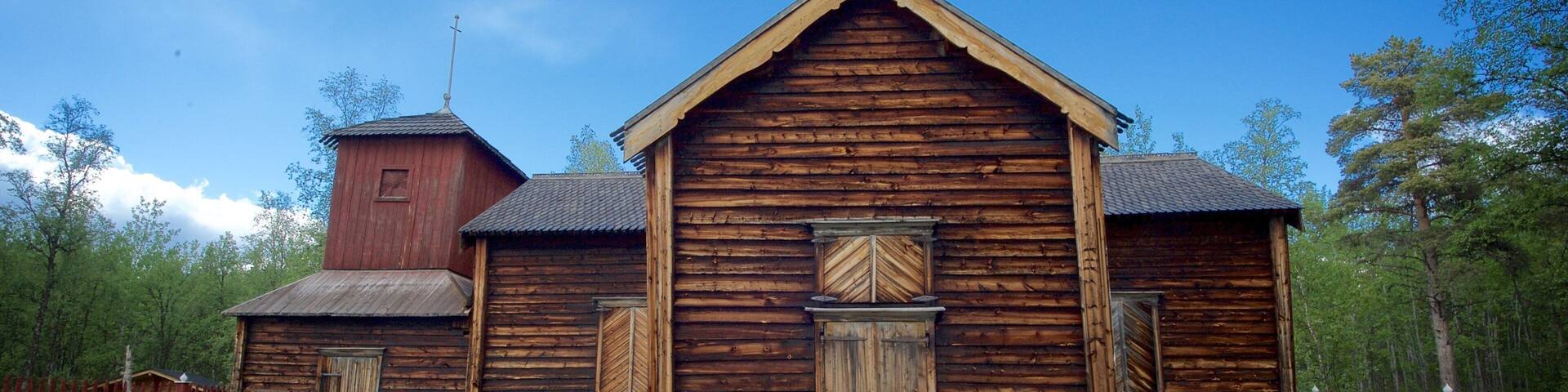 A wooden church with a bell tower and a wooden fence.