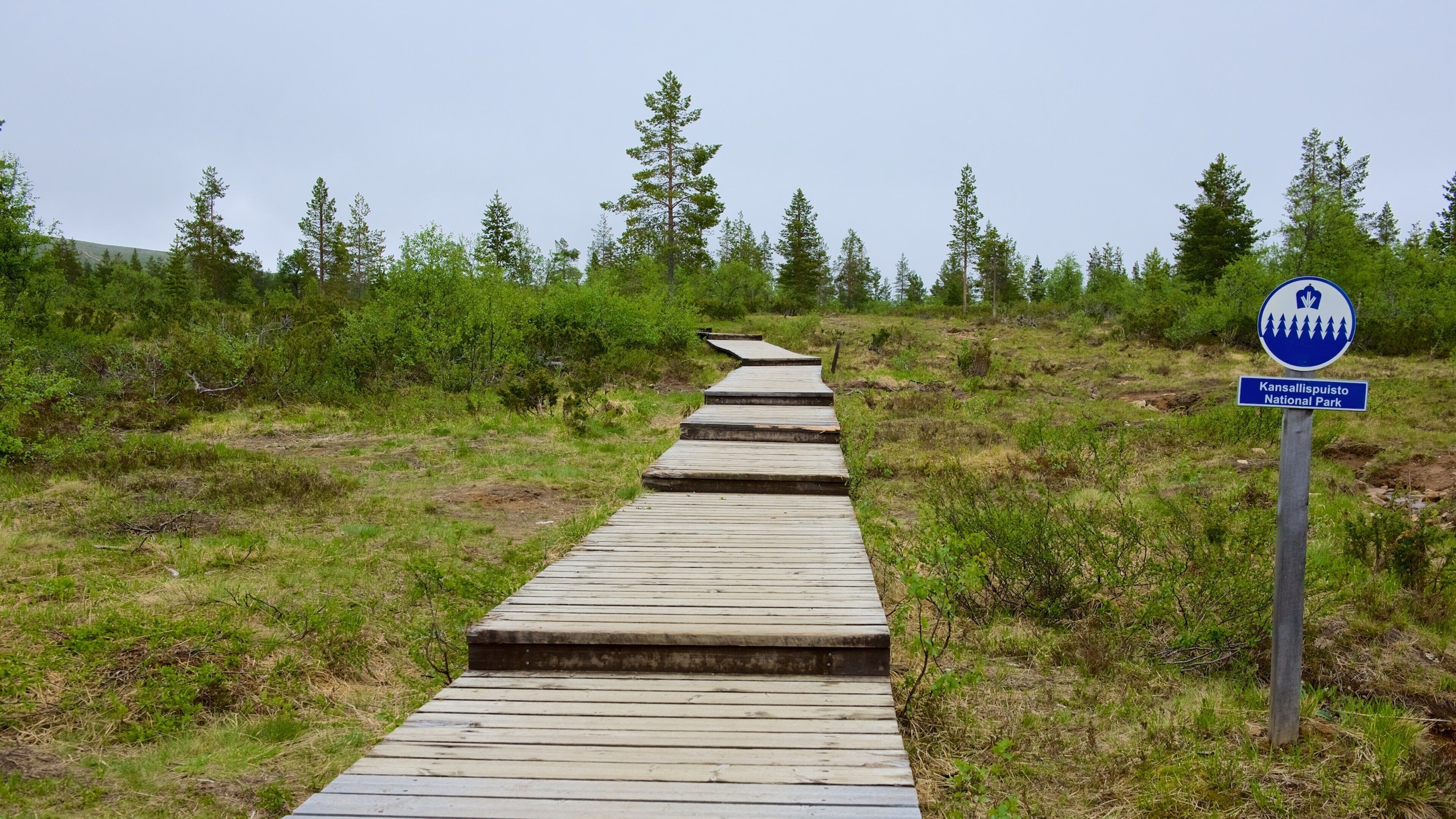 Urho Kekkosen kansallispuisto johon kuuluu kyltit, silta ja rauhalliset maisemat