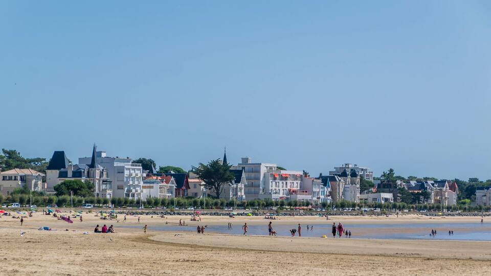 A beach with people and buildings in the background.