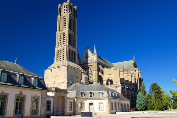 Uma igreja histórica com uma alta torre de sino e edifícios vizinhos.