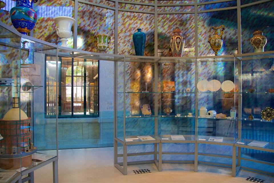 A museum interior with glass display cases containing various ceramic vases and plates.