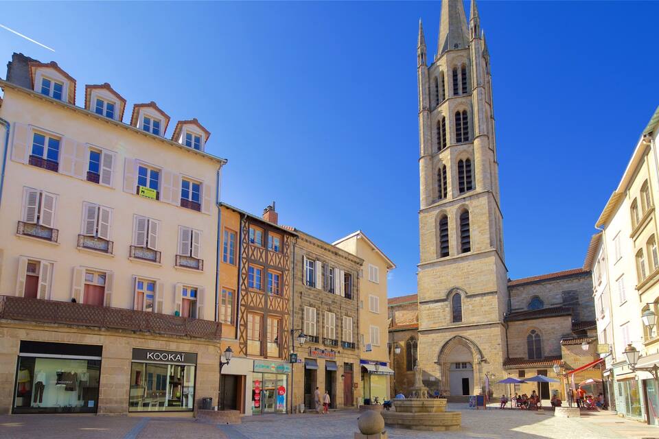 A historic town square with a prominent church tower, traditional buildings, and a statue.