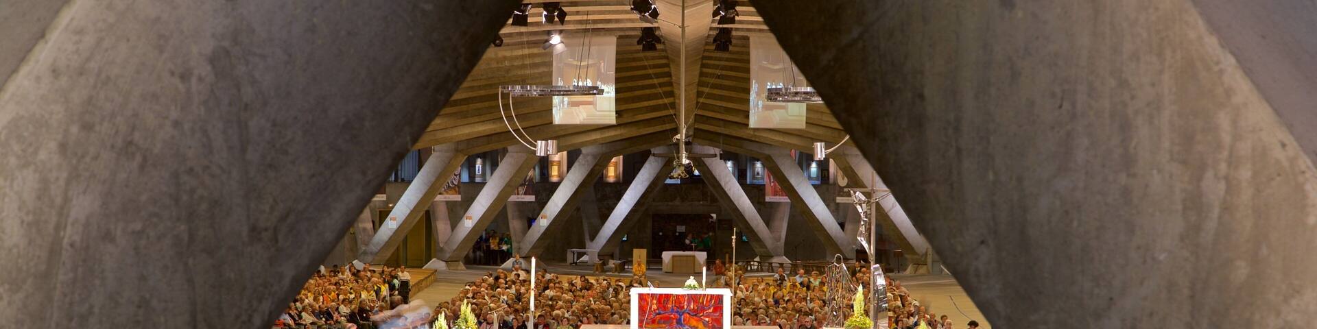 Basilica of St. Pius X featuring a church or cathedral and interior views as well as a large group of people