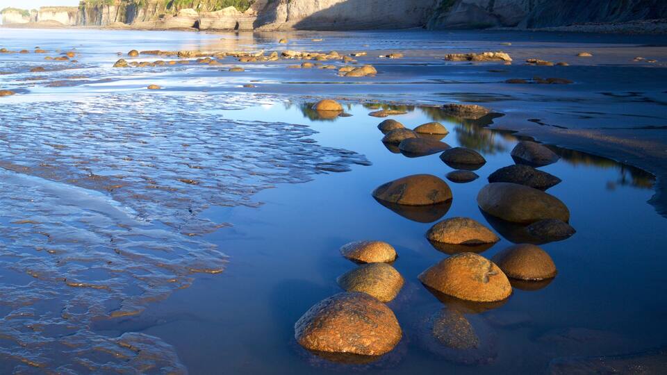 A rocky shoreline with smooth water reflecting the rocks.