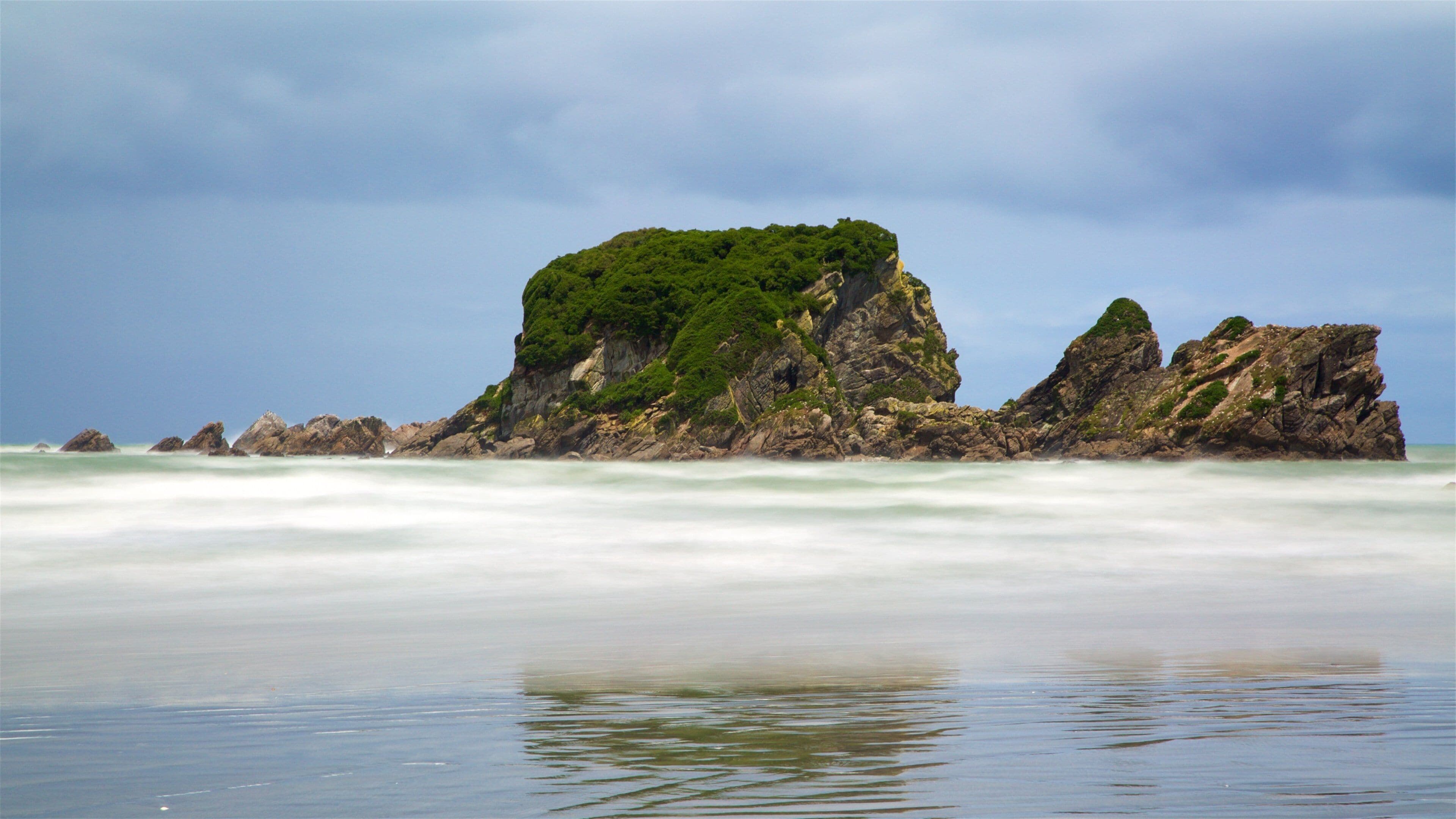 Tauranga Bay Seal Colony featuring a sandy beach, waves and rocky coastline