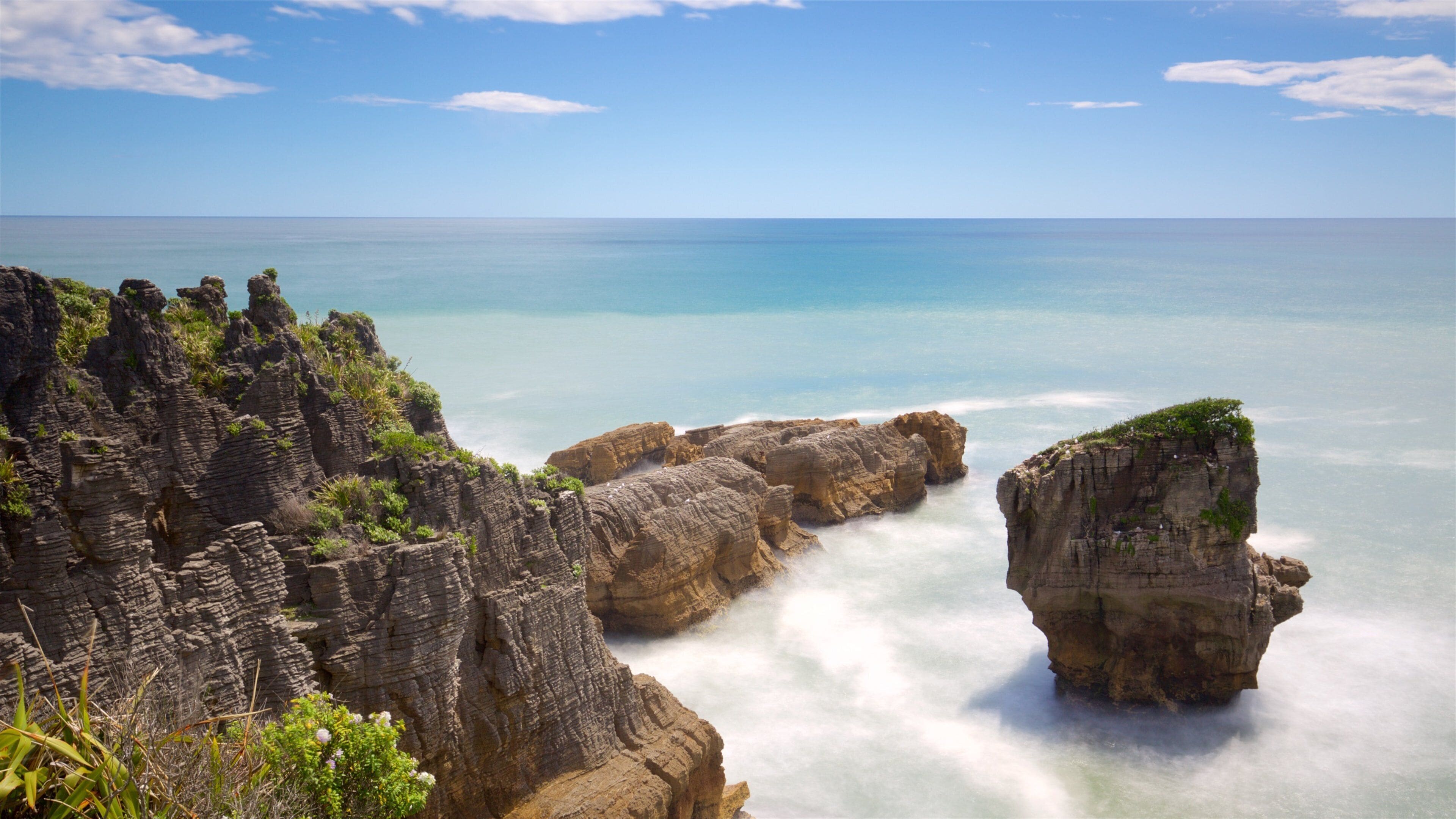 A coastal landscape with rocky cliffs and a clear blue sea.