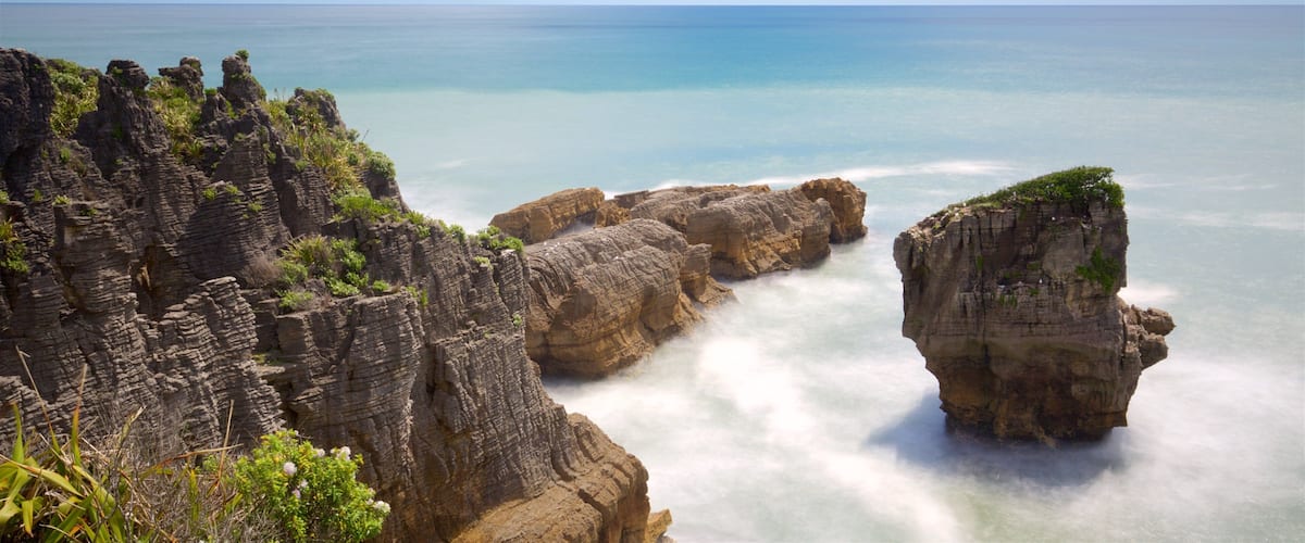 A coastal landscape with rocky cliffs and a clear blue sea.