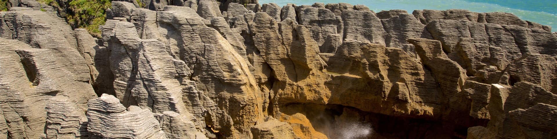 Pancake Rocks presenterar en hamn eller havsbukt, berg och klippig kustlinje