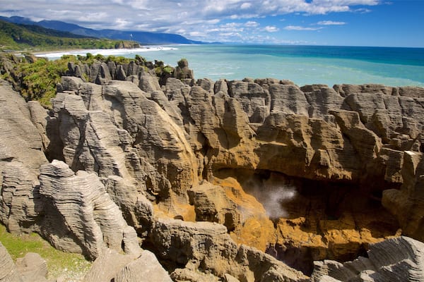 Pancake Rocks presenterar en hamn eller havsbukt, berg och klippig kustlinje