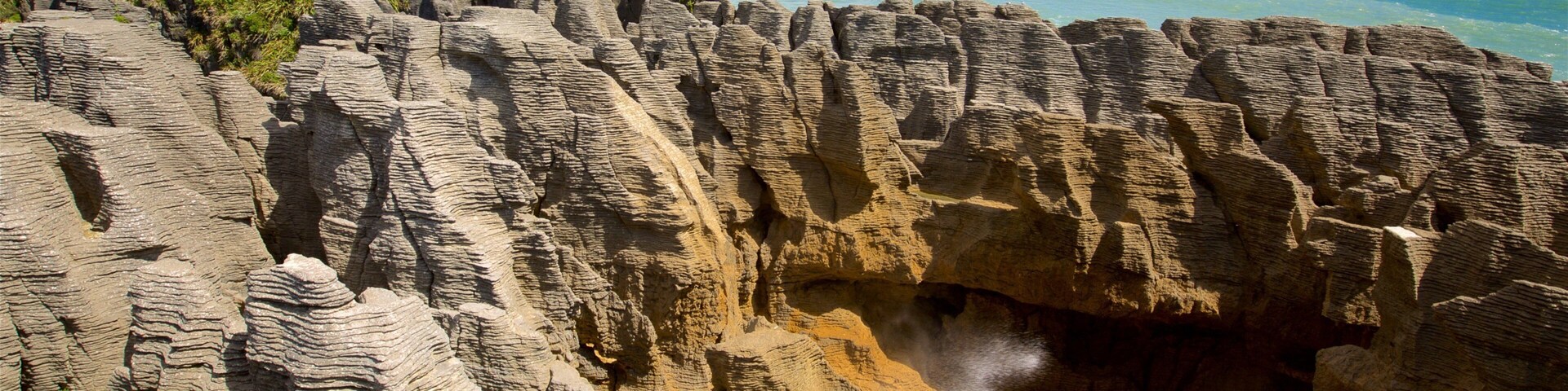 Pancake Rocks welches beinhaltet Berge, Bucht oder Hafen und FelskĂŒste