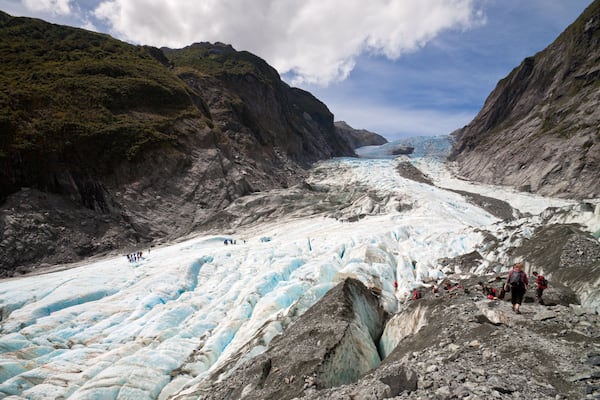 A glacier with people hiking on its surface.