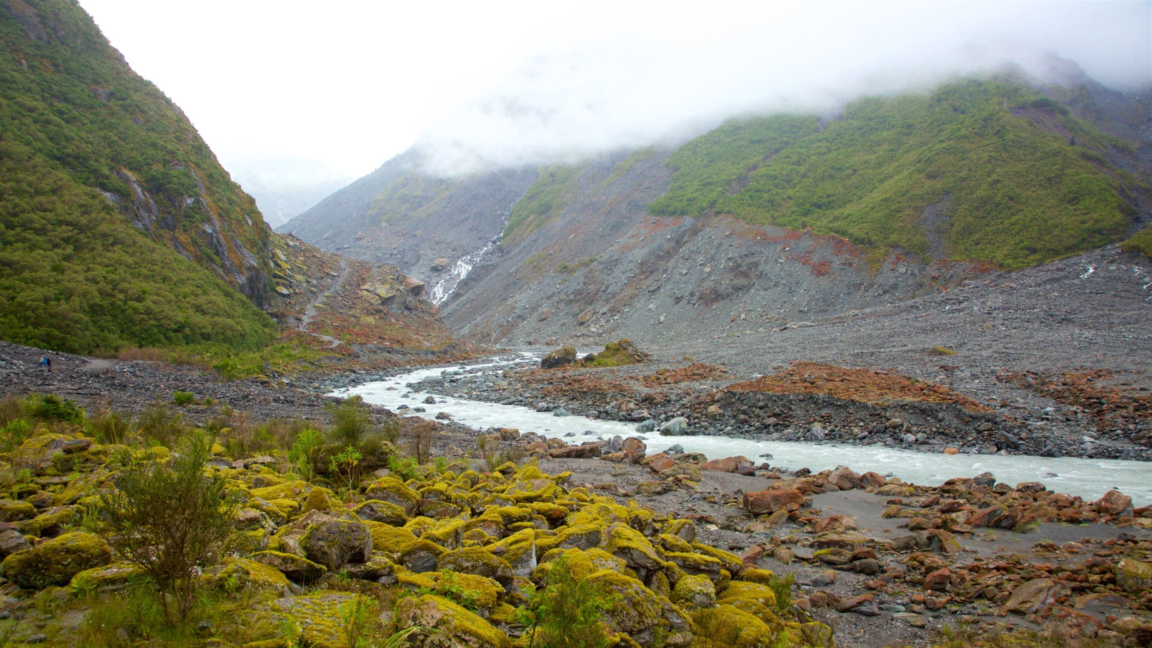 Fox Glacier which includes mist or fog, a river or creek and mountains