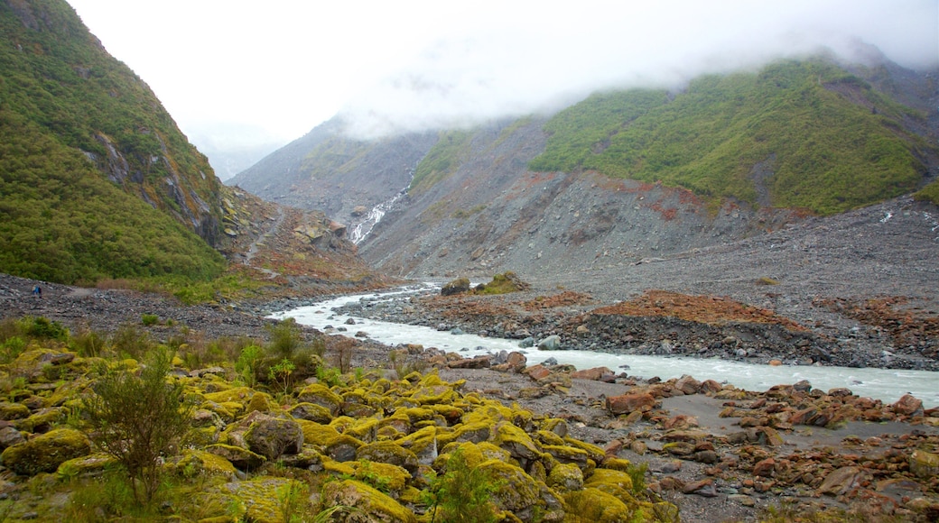 Fox Glacier which includes mist or fog, a river or creek and mountains