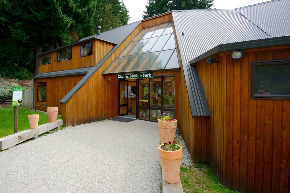 A wooden building with a sign reading "Kiwi Birdlife Park" and a gravel path leading to it.