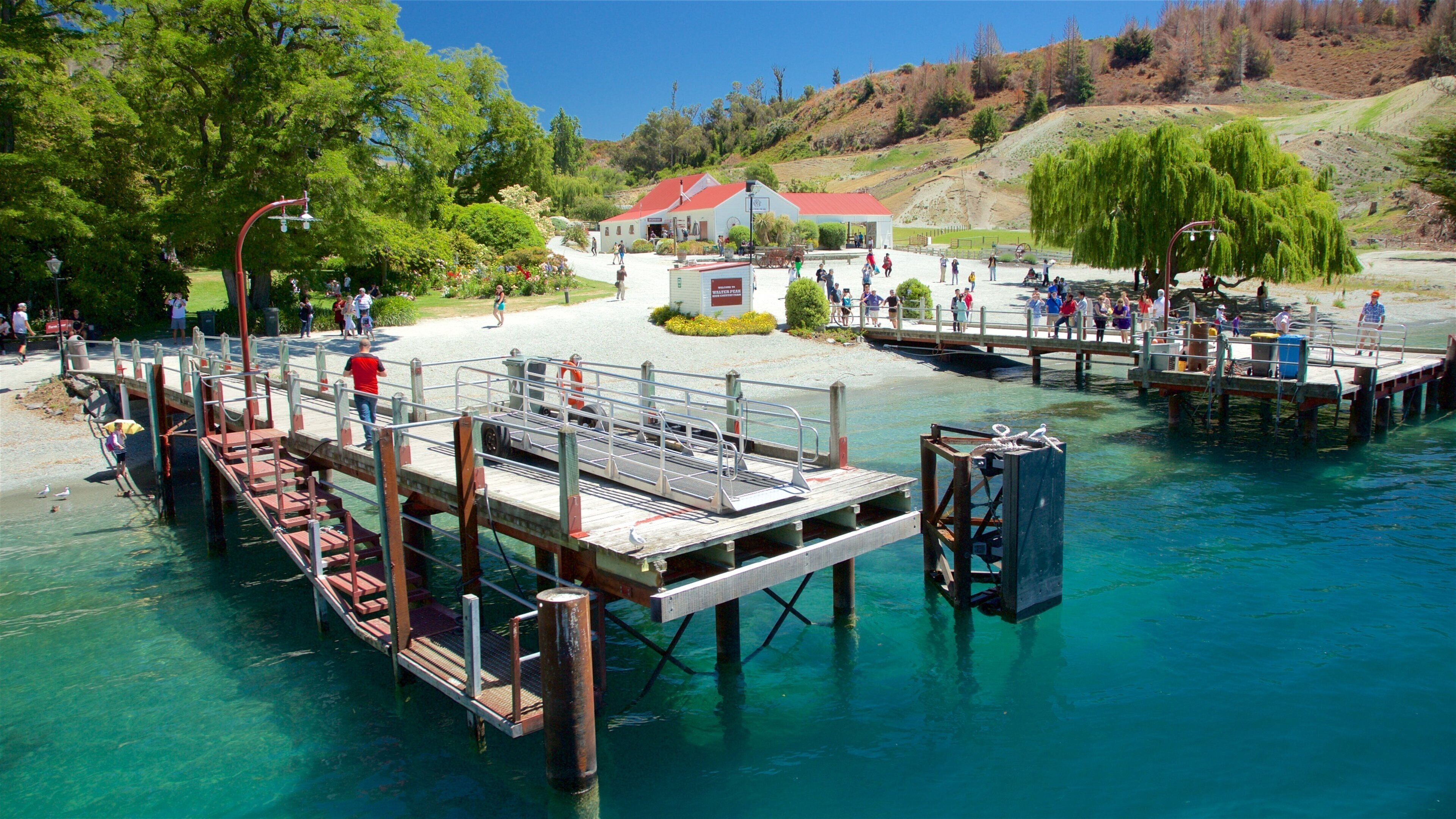A pier extending into clear blue water with people walking on it.