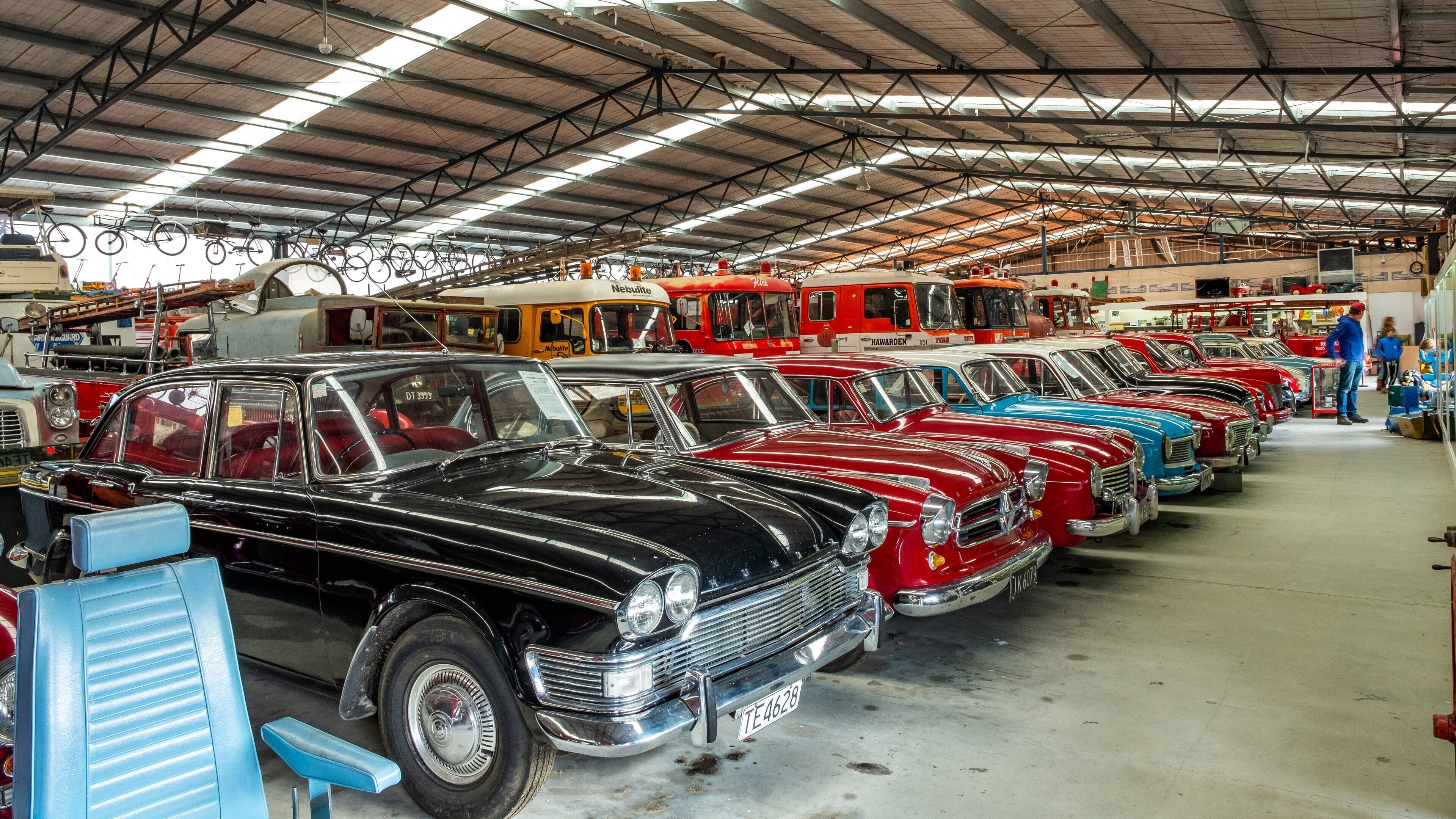 A vintage car show with rows of classic cars in a large indoor garage.