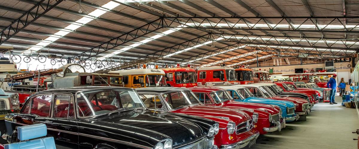 A vintage car show with rows of classic cars in a large indoor garage.