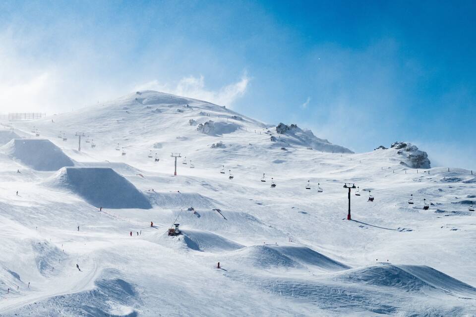 Pista de esquí nevada con remontes y esquiadores.