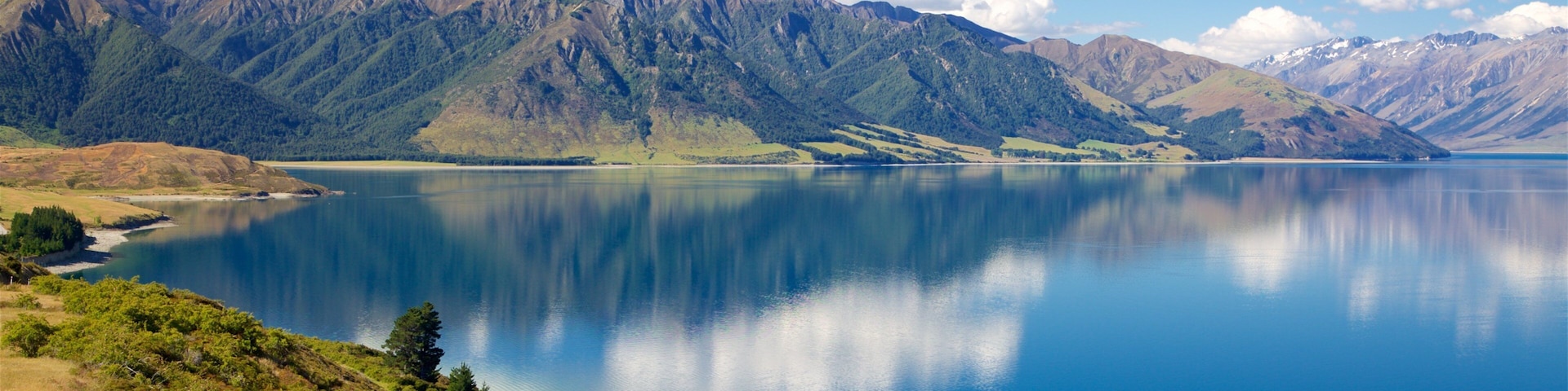 A calm lake surrounded by mountains under a clear sky.