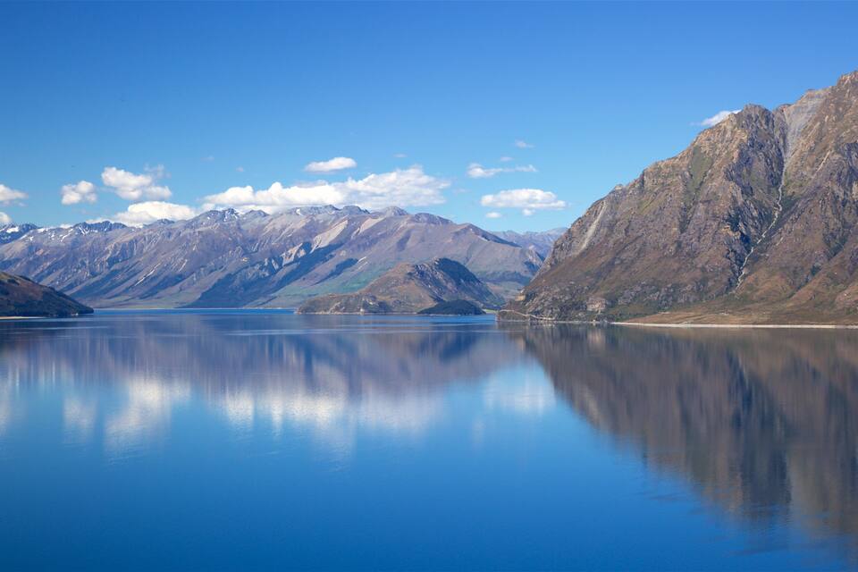 A calm lake surrounded by mountains with snow-capped peaks.