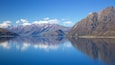 Un llac tranquil envoltat de muntanyes amb cims nevats.