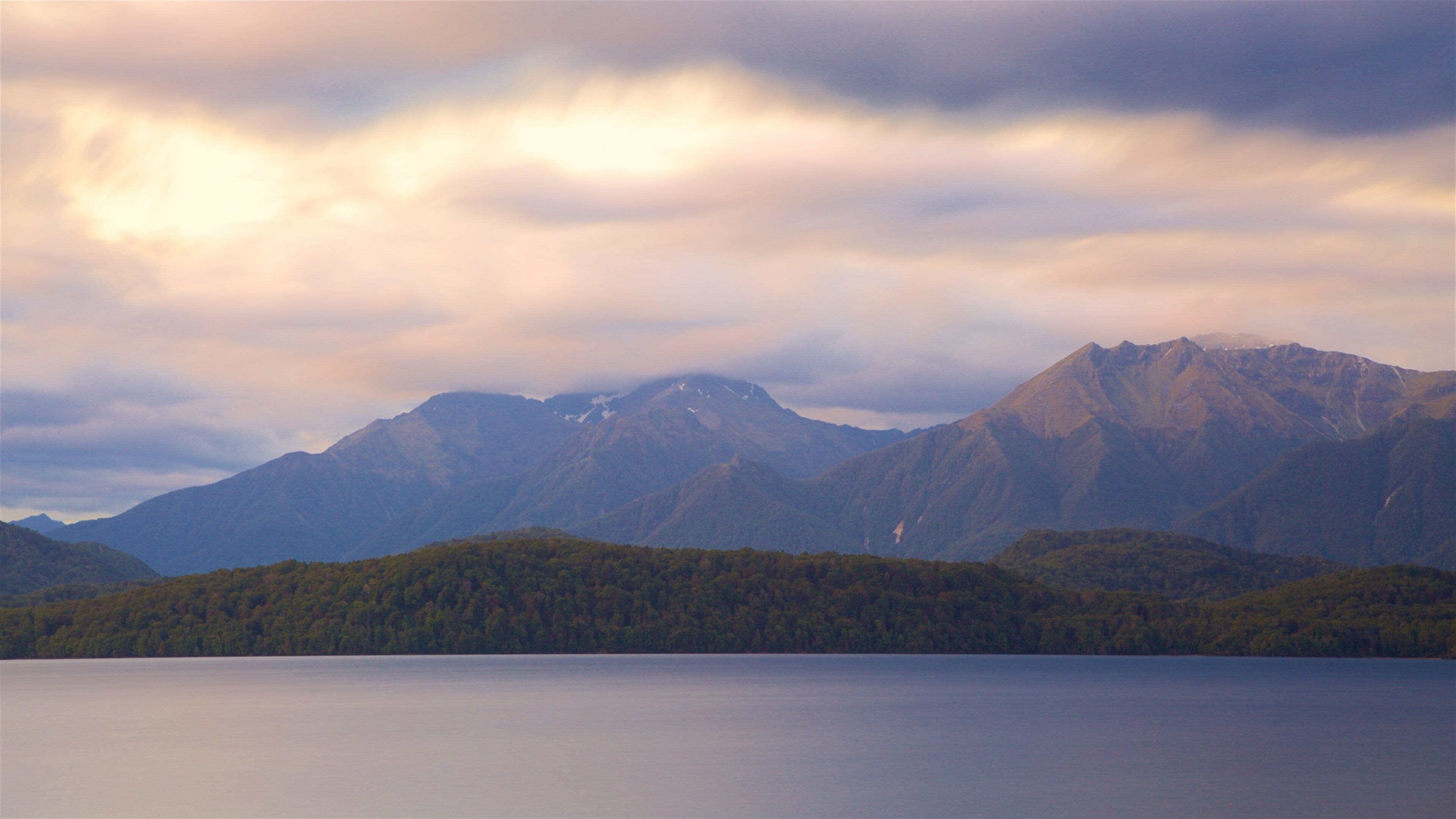 Lake Te Anau which includes a lake or waterhole, mountains and a sunset