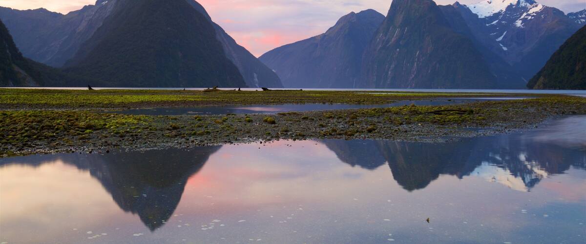 Mitre Peak which includes a pebble beach, a lake or waterhole and a sunset