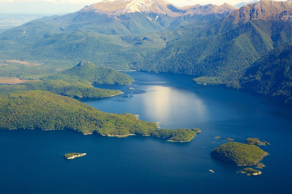A coastal landscape with a large body of water surrounded by green hills and mountains.