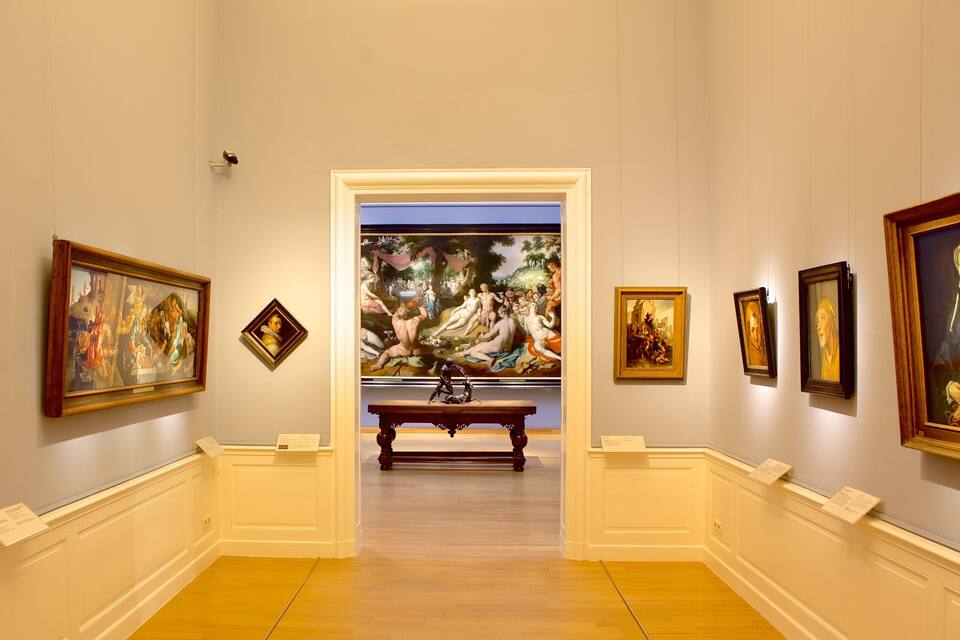 An art gallery with classical paintings and sculptures on display.