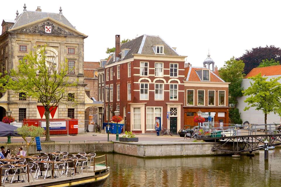 A canal with a boat docked on the left, surrounded by historic buildings with red and white facades.
